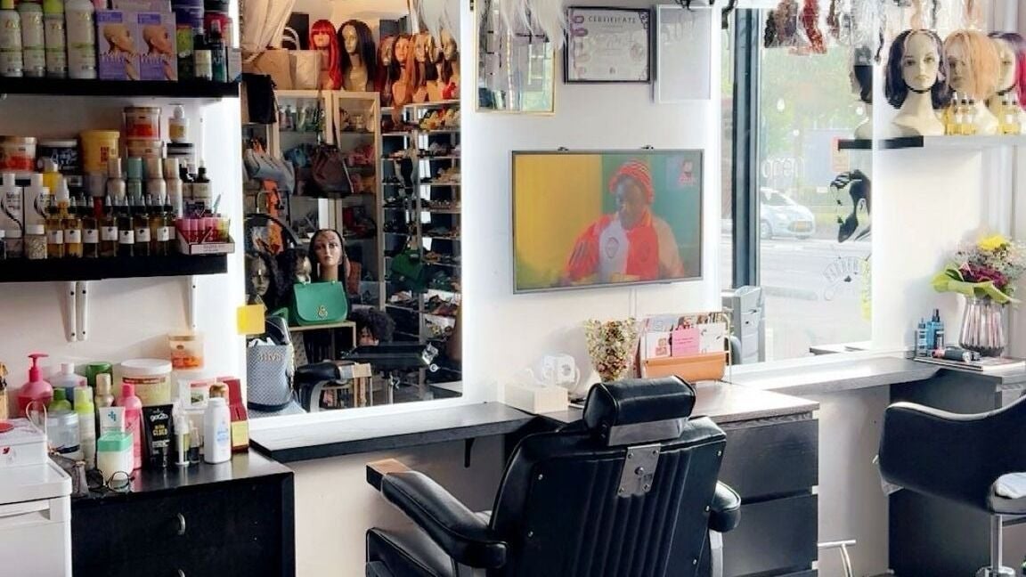 Een barberstoel voor de spiegel, met schappen vol producten en pruiken erachter