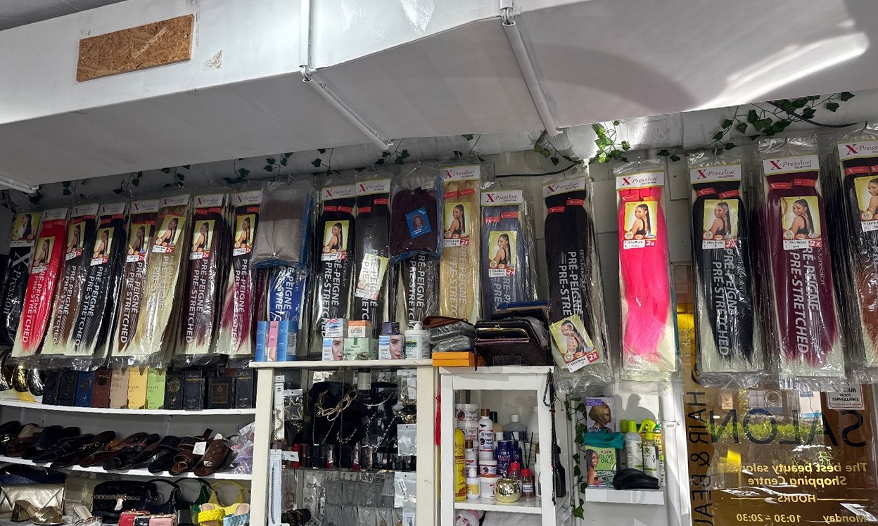 De wand met pre-stretched vlechthaar in alle kleuren, met schoenen en tassen eronder